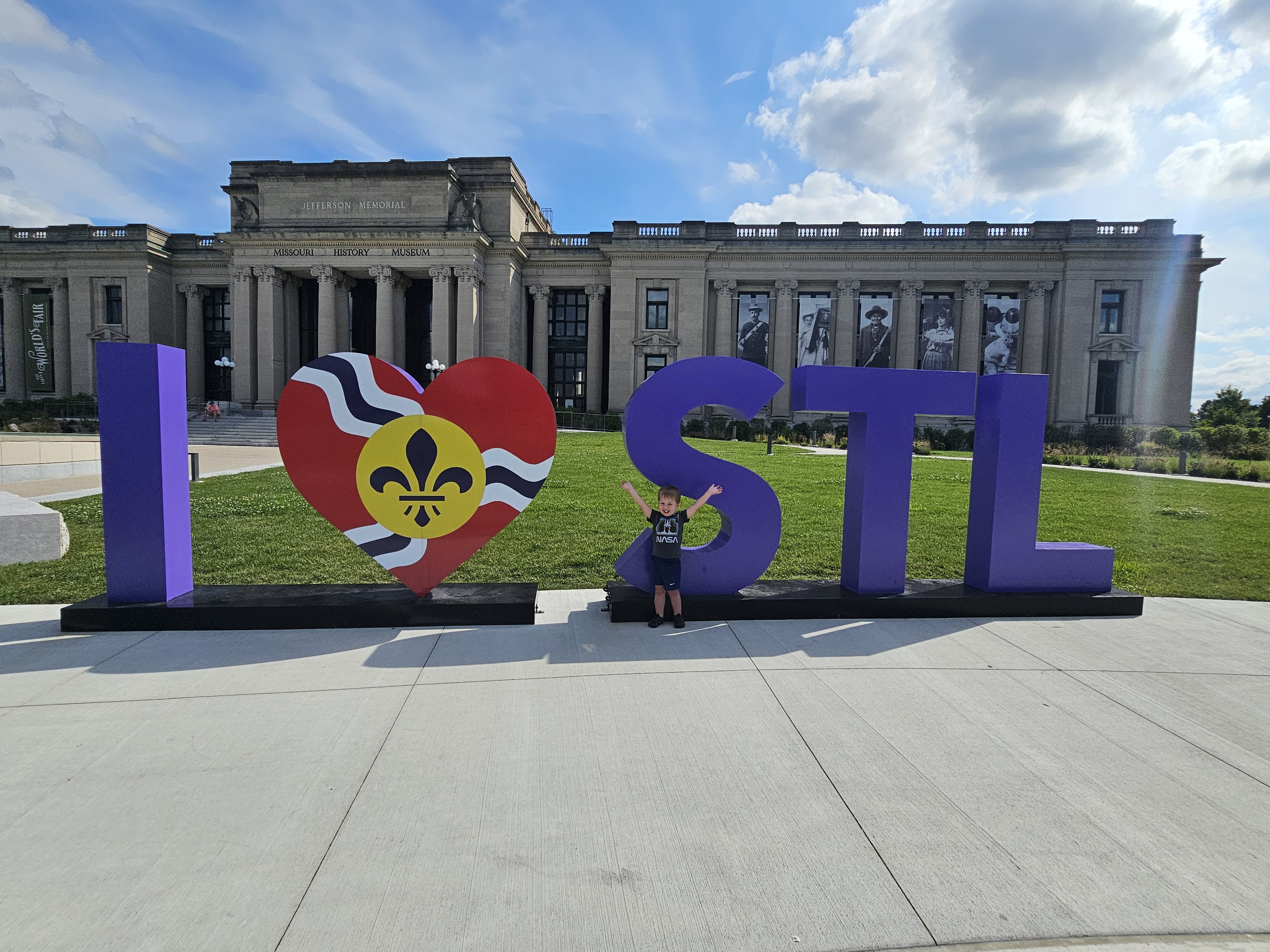 Image taken in front of the St. Louis History Museum with young boy standing with the I Love STL sign