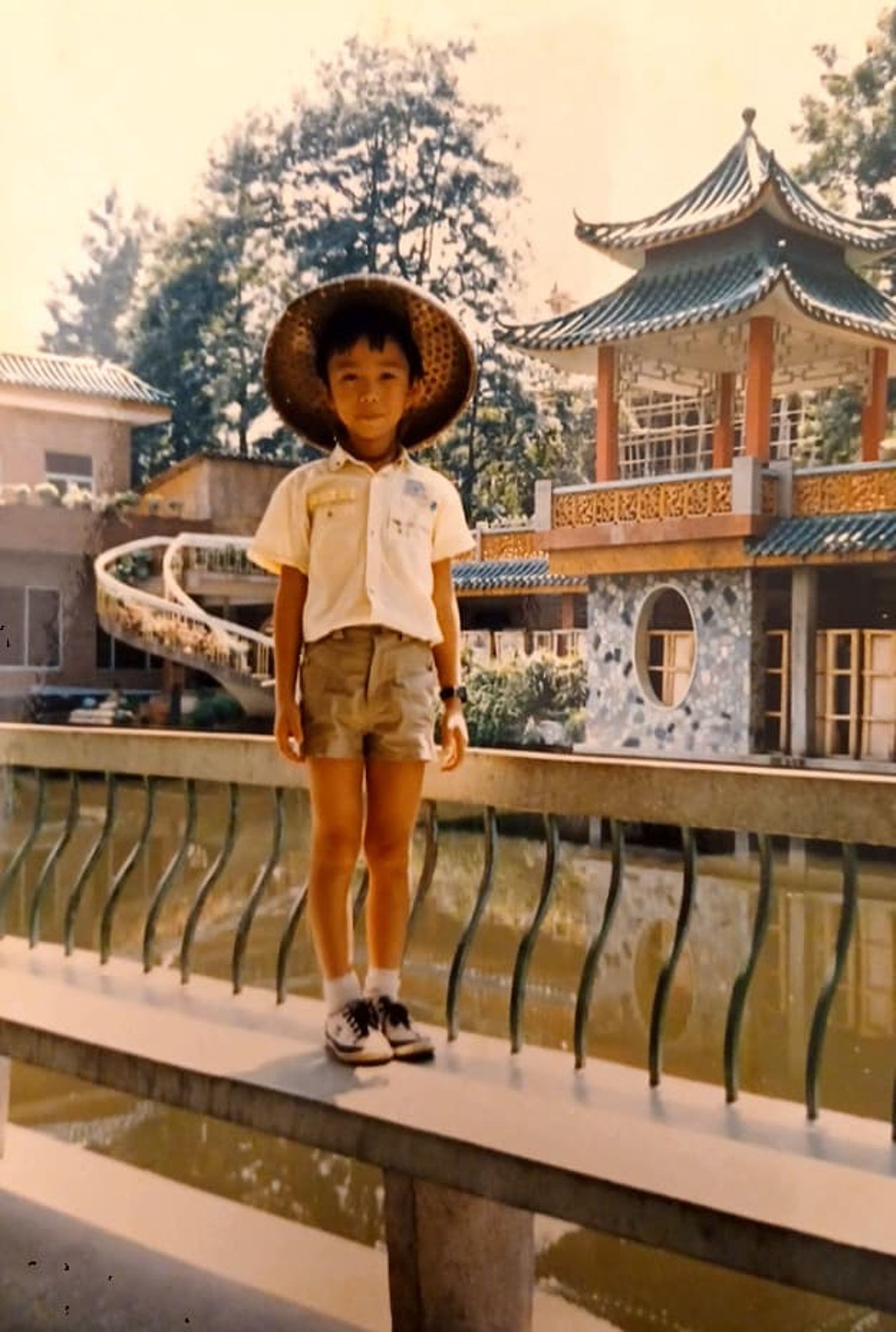 young boy wearing a hat in front of beautiful Asian architecture 