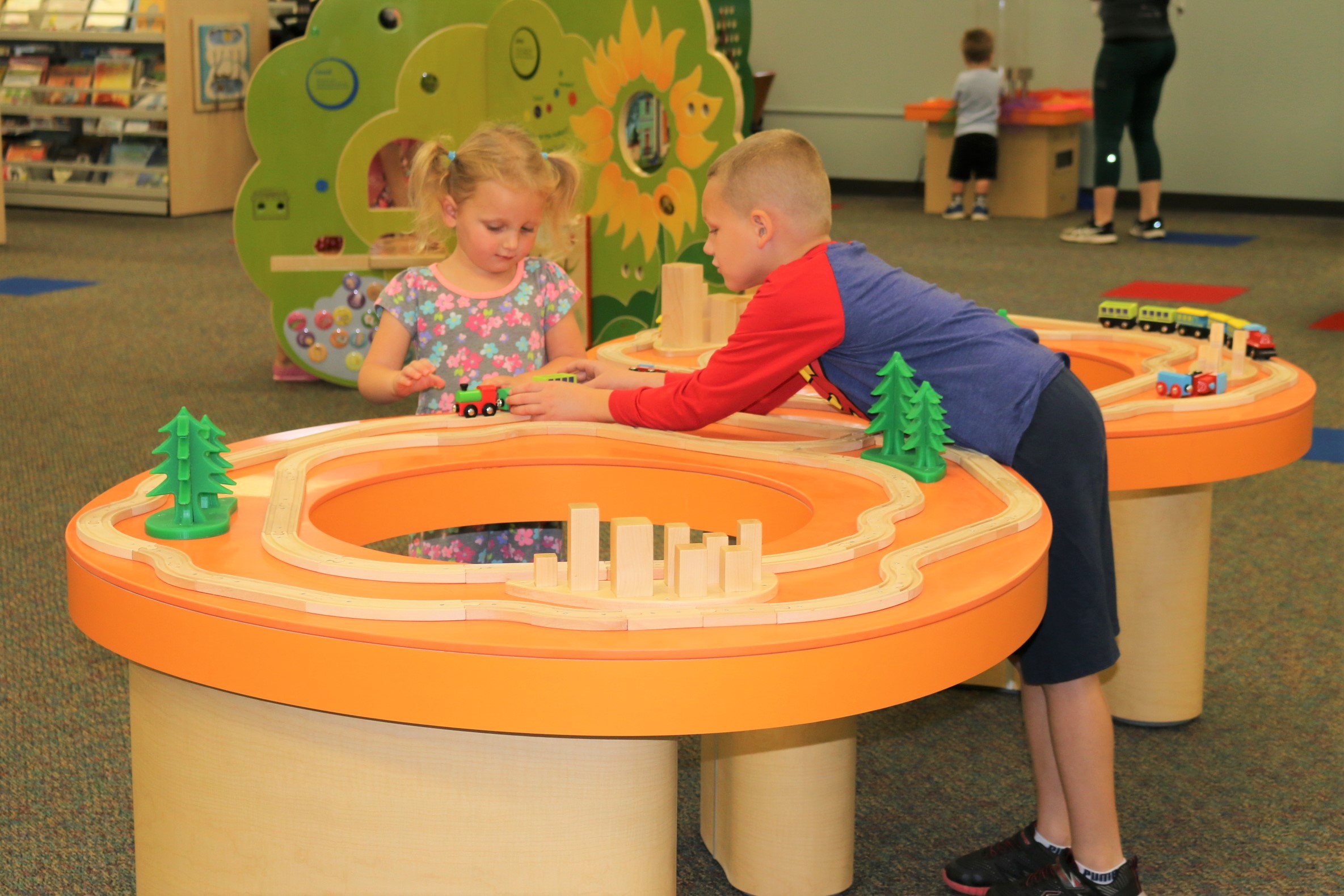 2 children playing with wooden train set